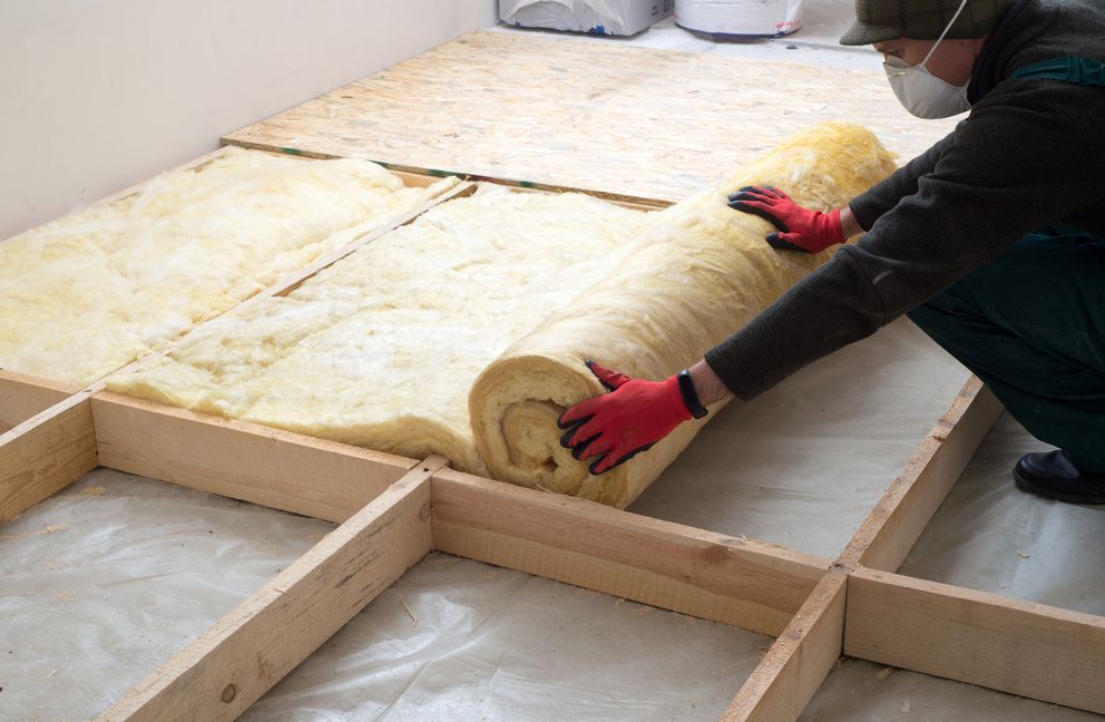 Ein Mitarbeiter mit Handschuhen und Maske baut Dämmmaterial ein